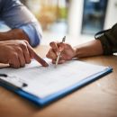 Two people look over an insurance claim document in an attempt to fill it out